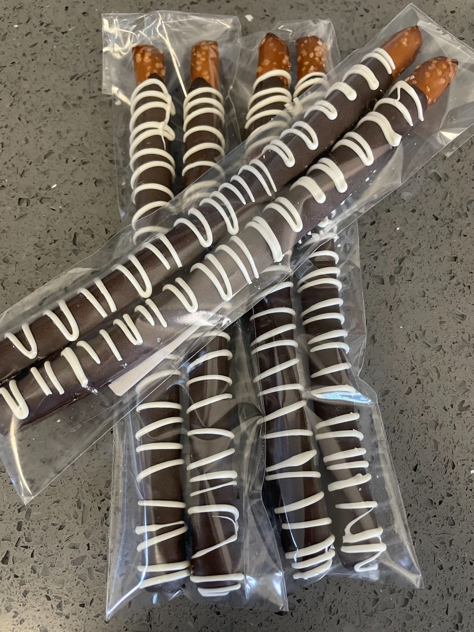 Chocolate covered pretzel rods drizzled with white chocolate in individual bags