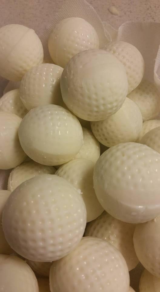 White chocolate cake balls decorated to look like dimpled golf balls, piled together